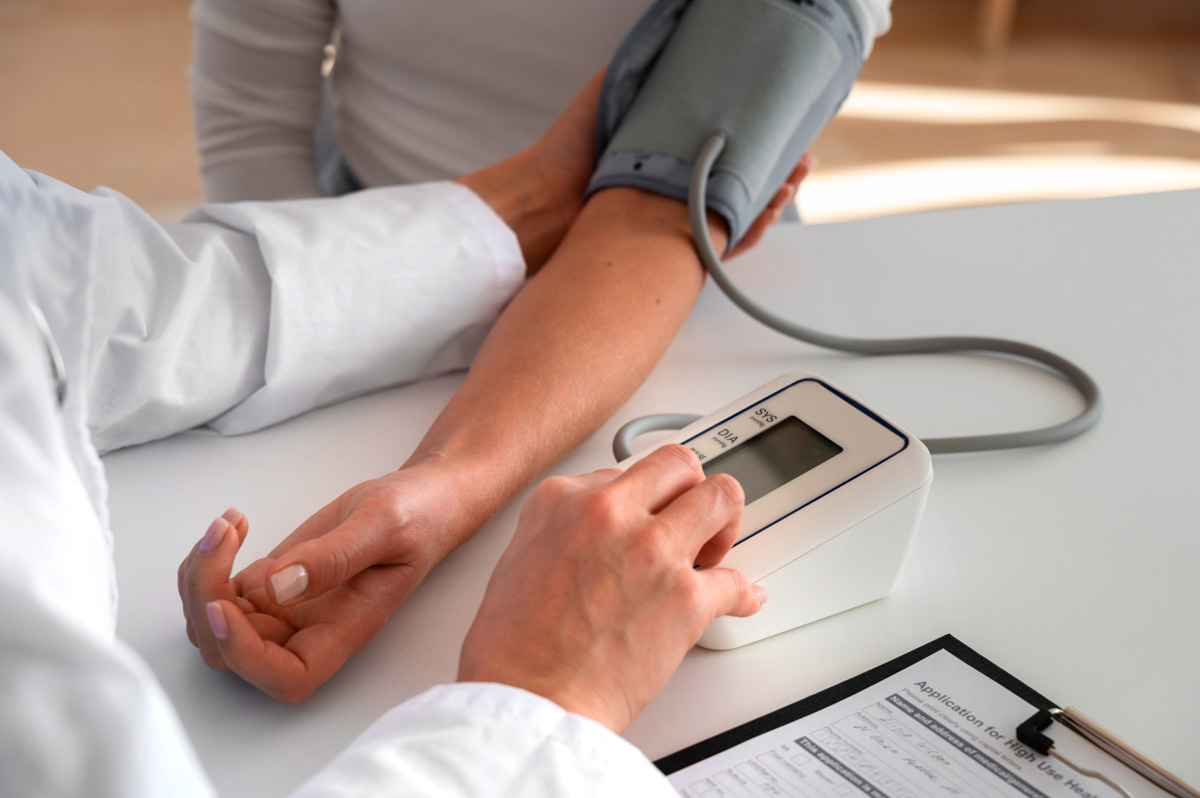 Arzt misst Blutdruck mit digitalem Blutdruckmessgerät am Arm einer Patientin